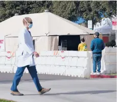  ?? ASHLEYLAND­IS/AP ?? A medical worker passes a tent outside the ER last week at UCI Medical Center in Irvine, California. The state is searching for nurses, doctors and other medical staff to meet demands as the coronaviru­s surge pushes hospitals to the breaking point.