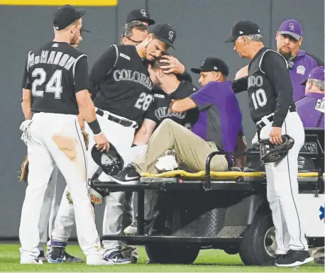  ?? Andy Cross, The Denver Post ?? Rockies third baseman Nolan Arenado consoles center fielder David Dahl as Dahl is carted off the field with a right ankle injury on Friday night at Coors Field.