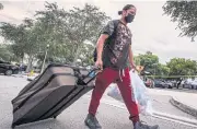  ??  ?? CLEARING OUT: A resident of the Crestview Towers Condominiu­m carries some belongings as he leaves the building deemed unsafe.