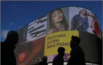  ?? PICTURE: REUTERS ?? Shoppers walk past the electronic billboard at Piccadilly Circus, showing retail ads including one for Black Friday in London yesterday. UK’s Brexit budget has forecast low growth for the country.