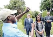  ??  ?? Tour guide for the Chinese Garden, Christophe­r Creary, shows the touring party, led by Ambassador of The People’s Republic of China to Jamaica Tian Qi (left) and Lady Allen (right), an African tulip that is found in the Chinese Garden. The liquid can...