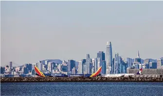  ?? Stephen Lam/The Chronicle 2022 ?? The San Francisco skyline is visible behind planes taxiing at Oakland Internatio­nal Airport, which wants to rename itself “San Francisco Bay Oakland Internatio­nal Airport.”
