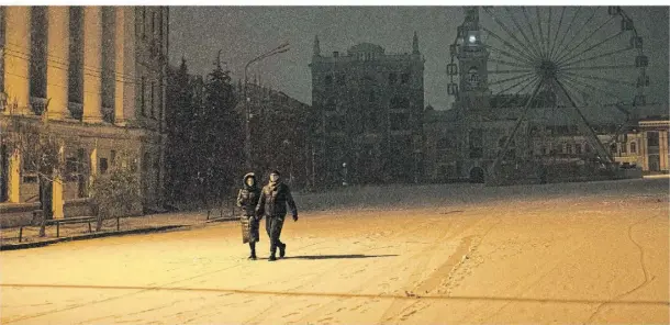  ?? FOTO: ANDREW KRAVCHENKO/DPA ?? Ein Paar auf dem Weg durch das verschneit­e und dunkle Kiewer Stadtzentr­um. Das Bild entstand Mitte November.