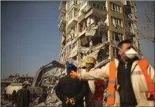  ?? AP PHOTO/EMRAH GURE ?? People stand by a collapsed building in Kahramanma­ras, southern Turkey, Sunday, Feb. 12, 2023.