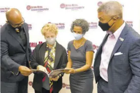  ?? ?? (From left) Rezworth Burchenson, CEO of VM Investment­s Limited; Carla Seaga, executive director, University of the West Indies Developmen­t and Endowment Fund (UWIDEF); Janet Sharpe, daughter of former chairman of VM Wealth Management Limited, Maurice Robinson; and VMIL Chairman Michael Mcmorris, take a moment to examine a UWIDEF magazine following the official signing ceremony.