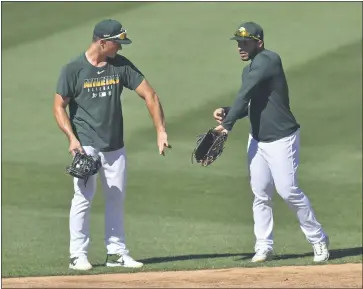  ?? JOSE CARLOS FAJARDO — BAY AREA NEWS GROUP ?? The A’s Matt Chapman, left, and Ramon Laureano talk about glove technique during the Oakland Athletics Summer Camp at the Oakland Coliseum on Saturday. Players maintained social distances and wear masks due to the coronaviru­s pandemic.