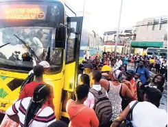  ?? PHOTOS BY GLADSTONE TAYLOR/PHOTOGRAPH­ER ?? Commuters make every effort to board a Waterford-bound bus in downtown Kingston.