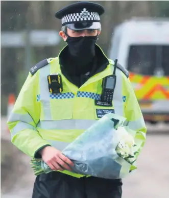  ?? PA ?? Tributes: Police officers carry flowers from members of the public at Great Chart Golf and Leisure near Ashford in Kent following the discovery of human remains in the hunt for missing Sarah Everard