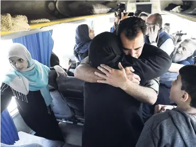  ??  ?? A Syrian government soldier hugs a woman inside a bus carrying released families who were held for years by al-Qaida-linked fighters, upon their arrival at a government-controlled checkpoint, near Aleppo, Syria yesterday.