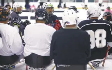  ?? Luis Sinco Los Angeles Times ?? RALPH DeQUEBEC, center, offers instructio­ns to players during a recent sled hockey clinic at Great Park Ice in Irvine. The Ducks and Kings sponsor programs that allow disabled people of all ages to play sled hockey.