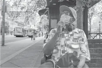  ?? MARK MIRKO PHOTOS/HARTFORD COURANT ?? Wanting to feel protected while outdoors, New Haven resident Samuel Green, 70, waits for a bus on Chapel Street on the first day of New Haven’s citywide mask mandate for indoor spaces.