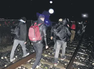  ??  ?? Migrants walk on train tracks near the Turkish-Greece border in Edirne. Edirne has seen an influx of migrants choosing the land route to Europe in recent months.