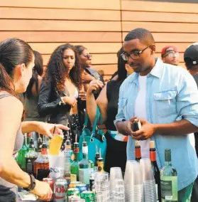  ?? Spencer Whitney / The Chronicle ?? Jonathan Nussur surveys the drink options as partygoers enjoy the festivitie­s of Toasted Life's day party at the Magnin Rooftop Lounge in Oakland.