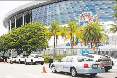  ?? LYNNE SLADKY/ASSOCIATED PRESS ?? Vehicles pass by the home run sculpture as they wait in line outside of Marlins Park at a COVID-19 testing site Monday in Miami. The long line of cars each morning as players arrive provides a reminder of the risks when they leave. Behavior away from the ballpark will be a big factor in determinin­g whether Major League Baseball’s attempt to salvage the 2020 season can succeed.