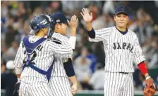  ?? THE ASSOCIATED PRESS ?? Japan’s Hayato Sakamoto, right, celebrates Tuesday with catcher Seiji Kobayashi and closer Kazuhisa Makita, center, after beating Cuba 11-6 in their first-round game of the World Baseball Classic in Tokyo.