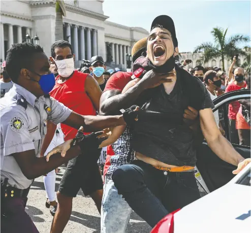  ?? YAMIL LAGE / AFP VIA GETTY IMAGES ?? A protester is arrested during a demonstrat­ion against Cuban President Miguel Diaz-canel in Havana on Sunday.