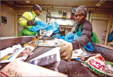  ?? AFP ?? People work on the recycling line sorting newspapers in Eskilstuna. The city plans to capture more CO2 than it emits and be independen­t of fossil fuels by 2045.