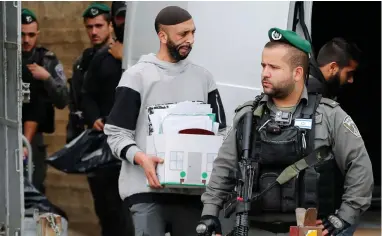  ?? PICTURE: REUTERS ?? FORCED REMOVAL: An undercover Israeli security officer carries a box with documents seized from a Palestinia­n map office as Israeli police close the office in East Jerusalem. The office kept records of Palestinia­n-owned land and property transactio­ns.