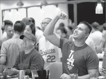  ?? Allen J. Schaben Los Angeles Times ?? THE DODGERS’ return to the World Series after a 29-year drought has given fans reason to celebrate. Above, Cesar Loya, right, cheers on the Dodgers while watching Tuesday’s Game 1 at Tom’s Urban at L.A. Live.