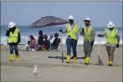  ?? PHOTOS BY RINGO H.W. CHIU — THE ASSOCIATED PRESS FILE ?? A family is under an umbrella as workers continue to clean the contaminat­ed beach in Huntington Beach. California’s uneasy relationsh­ip with the oil industry is being tested again by the latest spill to foul beaches and kill birds and fish off Orange County.