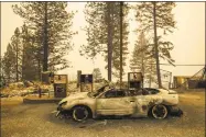  ?? Noah Berger / Associated Press ?? As the campfire burns nearby, a scorched car rests by gas pumps near Pulga, Calif., on Sunday.