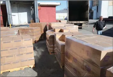  ?? The Sentinel-Record/Richard Rasmussen ?? LARGE DONATION: Ted Thompson, right, director of the Project HOPE Food Bank, walks past 27 palettes containing 42,000 pounds of food sitting outside the bank’s warehouse at 915 Gaines Ave. The food was donated Wednesday morning by The Church of Jesus Christ of Latter-day Saints in Salt Lake City as part of its Light the World initiative.