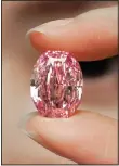  ??  ?? An ultra-rare 14.83-carat diamond that is one of the largest internally flawless, fancy vivid purple-pink gem ever graded by the Gemologica­l Institute of America is displayed by a model at a Sotheby’s auction room in Hong Kong on Oct 12. The diamond will be on sale in Geneva on Nov 11. (AP)