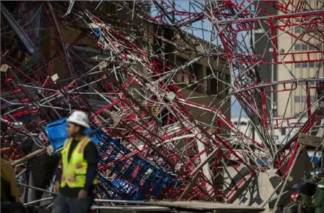  ?? Daniel Carde/The San Antonio Express-News via AP ?? Constructi­on workers clean up collapsed scaffoldin­g Friday along East Martin Street in San Antonio. Officials say three bystanders were slightly hurt as a 100-foot section of scaffoldin­g collapsed amid 50 mph winds from a system linked to Tropical Storm Imelda.