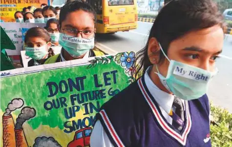  ?? AFP ?? Indian schoolchil­dren wearing pollution masks hold placards as they participat­e in a march, organised by United Nations Informatio­n Centre, to raise awareness of the alarming levels of air pollution in New Delhi yesterday.