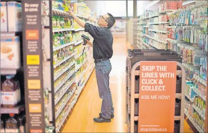  ?? CP PHOTO ?? Grant Bone, Department Manager for Loblaw’s ‘Click and Collect’ gathers a customer’s order at one of the grocery chain’s outlets in Toronto on Thursday.