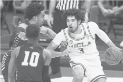  ?? MARK HUMPHREY/AP ?? UCLA’s Johnny Juzang (3) is defended by Abilene Christian’s Coryon Mason, left, and Reggie Miller (10) the second round of the NCAA Tournament on Monday.