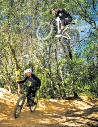  ?? Photos by Sarahbeth Maney / Special to The Chronicle ?? Left: Former Redding mayor and avid mountain biker Brent Weaver rides on the Fisherman’s Trail. Above: Ryan Schuppert jumps over Taylor Smith on the Enticer Trail.