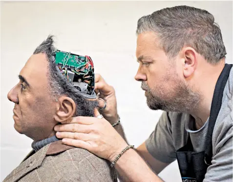  ??  ?? Prosthetic­s expert Mike Humphrey of Engineered Arts checks on one of the company’s creations at its base in Cornwall. The company specialise­s in life-size humanoid robots