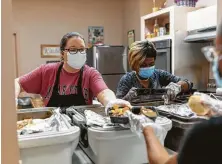  ?? Gustavo Huerta / Staff photograph­er ?? Volunteers Janece Young, left and Velma Pierson package hot meals at the Sleepy Hollow Multipurpo­se Building in Tamina.