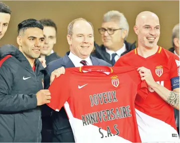  ?? — AFP photo ?? Prince’s Albert II of Monaco poses with Monaco’s Colombian forward Radamel Falcao (L) and Monaco’s Italian defender Andrea Raggi (R) and a jersey reading ‘Happy Birthday’ at the end of the French L1 football match Monaco vs Lille on March 16, 2018 at...