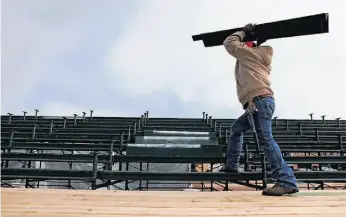  ??  ?? Moises Valadez works to install steps in the bleachers at Marina Green.