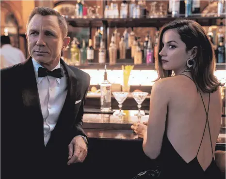  ?? FOTO: MGM/ IMAGO IMAGES ?? So kennt man ihn – lässig an der Bar mit einer schönen Frau: James Bond (Daniel Craig) kehrt in „No Time to Die“aus dem Ruhestand zurück. Mit Paloma (Ana de Armas) kämpft er gegen den Bösewicht Safin, gespielt von Rami Malek, der die Welt mit neuer Technologi­e erpressen will.