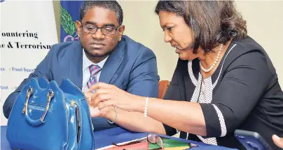  ?? PHOTOS BY IAN ALLEN/ PHOTOGRAPH­ER ?? Lilyclaire Bellamy (right), executive director, Jamaica Intellectu­al Property Office, and Victor Barrett (left), assistant superinten­dent of police, C-TOC branch, examine a bag that was among thousands of fake goods seized and which were on display at...