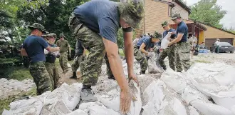  ?? John Woods/The Canadian Press ?? Soldiers from 17 Wing in Winnipeg sandbag in St. François Xavier, Man., on Tuesday. Several days of frantic sandbaggin­g is paying off in a precaution­ary measure as the Assiniboin­e River reaches further crests.