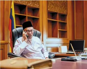  ?? ?? At ease: anwar on his first day at the Prime minister’s Office in Putrajaya handling congratula­tory phone calls from world leaders, some of whom he knows personally. — SADIQ asyraf/pmo