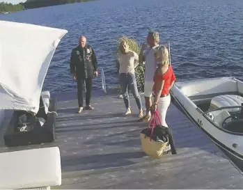  ??  ?? A security video shows Linda O'leary, in blue jeans and white top, wife of celebrity investor Kevin O'leary, in black shirt, with the speedboat before they left for a neighbour's cottage on the evening of a fatal boat crash.
