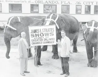  ?? SENTINEL FILE PHOTOS ?? In April 1957, James E. Strates, left, and Tom Corbett of the Greater Orlando Chamber of Commerce touted Strates Shows’ promotion of Orlando as the City Beautiful, emblazoned on a railroad car behind them. Elephants are no longer used in carnival midways.