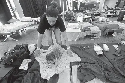  ?? AP Photo/Gerald Herbert ?? n Katrina Johnson spreads a blanket for her 4-month-old daughter, Blakely, at an evacuation shelter Friday at Lake Charles Civic Center in Lake Charles, La.