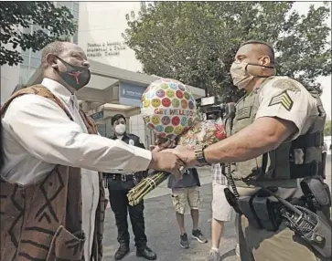  ?? Genaro Molina Los Angeles Times ?? NAJEE ALI, director of Project Islamic Hope, left, hands Sgt. Larry Villareal of the Los Angeles Sheriff’s Department gifts Monday for the two deputies recovering at St. Francis Medical Center in Lynwood.