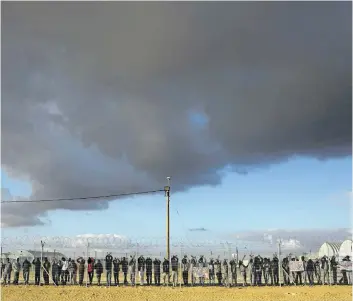  ?? ODED BALILTY/ THE ASSOCIATED PRESS FILES ?? In this Feb. 17, 2014, file photo, African migrants stand inside Holot detention centre as others protest outside against the detention centre near Ktsiot in the Negev Desert in southern Israel.