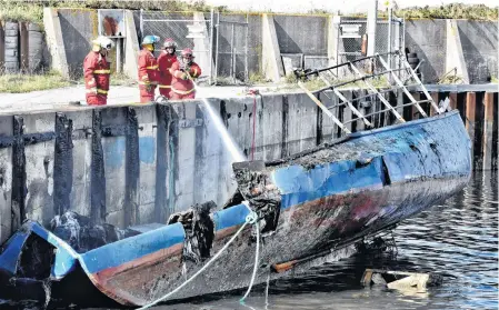  ?? TINA COMEAU • SALTWIRE NETWORK ?? Members of the Little Brook Volunteer Fire Department train water on the charred remains of a boat that was reported on fire Monday morning. The boat belongs to a member of the Sipekne’katik First Nation. The RCMP is investigat­ing.
