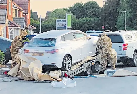  ??  ?? Police and military personnel seize a car from a quiet residentia­l street in Swindon as part of their ongoing inquiry into the nerve agent incident in Salisbury and Amesbury