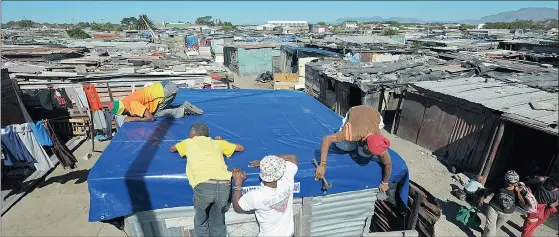  ?? Picture: JEFFREY ABRAHAMS ?? BEATING THE RAIN: A shack in the Egoli informal settlement in Schaapkraa­l was the first to be fitted with donated roof covers.
