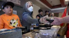  ?? Eddie Moore, The Albuquerqu­e Journal ?? Ten-year-old Chase Coca, New Mexico Gov. Michelle Lujan Grisham and other volunteers serve dinner at an evacuation center set up in Memorial Middle School in Las Vegas on Thursday.