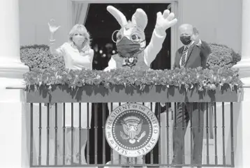  ?? EVAN VUCCI/AP ?? No Easter Egg Roll again at White House: First lady Jill Biden, a special guest and President Joe Biden wave from the White House on Monday. The traditiona­l Easter Egg Roll was canceled for a second consecutiv­e year due to the pandemic. The maskwearin­g Easter Bunny was played by Air Force Lt. Col. Brandon Westling, a military aide to the president.